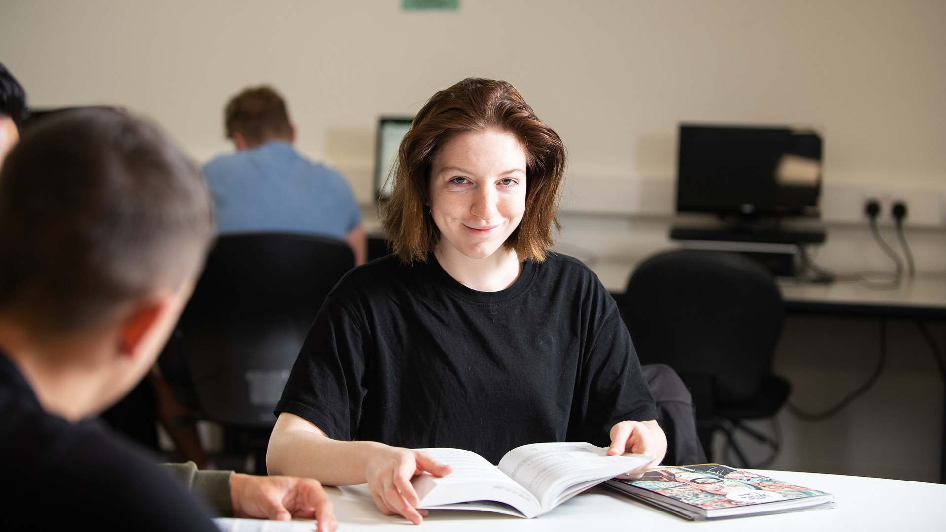 Smiling student reading a book in the library.