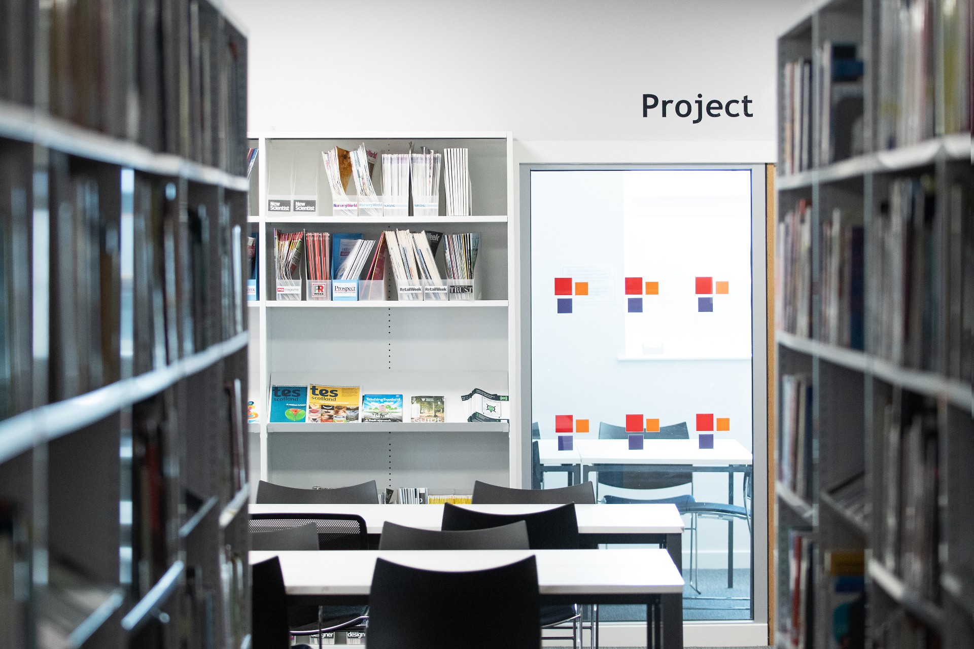 Book shelves in the library, with empty tables and chairs. 