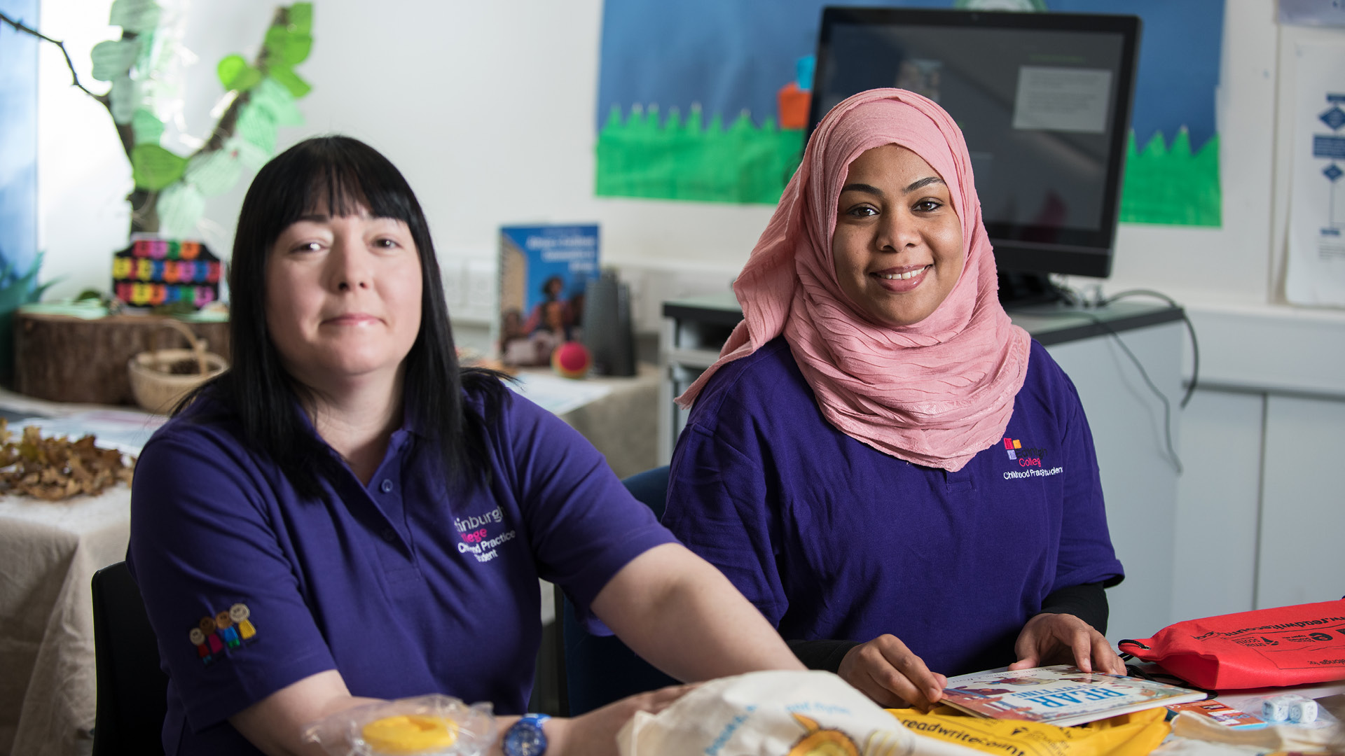 Childcare students looking at children's books in a classroom. 