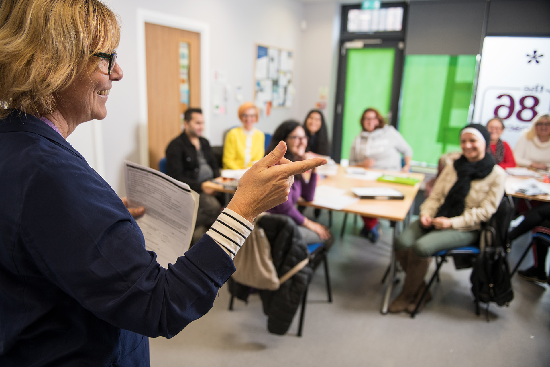 ESOL lecturer teaching in front of a classroom of students.  