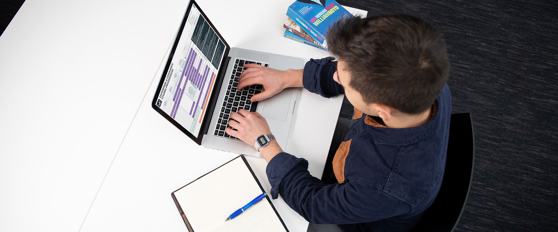 Student at a desk in the library with their laptop open, looking at Edinburgh College progression maps on the screen.