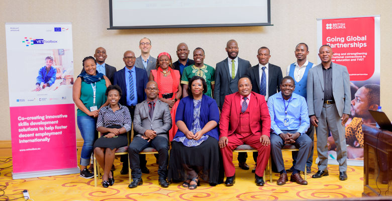 A diverse group of professionals poses for a photo in front of a banner promoting skills development for employment globally.