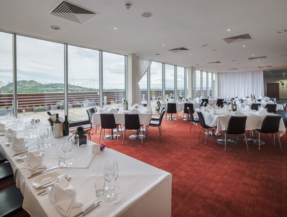 Restaurant at Edinburgh College set up for an event, with white table clothes, glass wear and cutlery on tables.