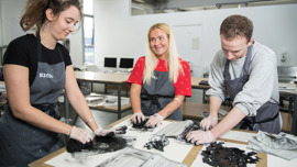 Art students wearing aprons working in their art classroom.