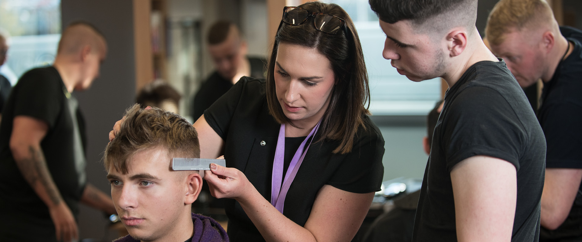 Lecturer is demonstrating a barbering technique to students.