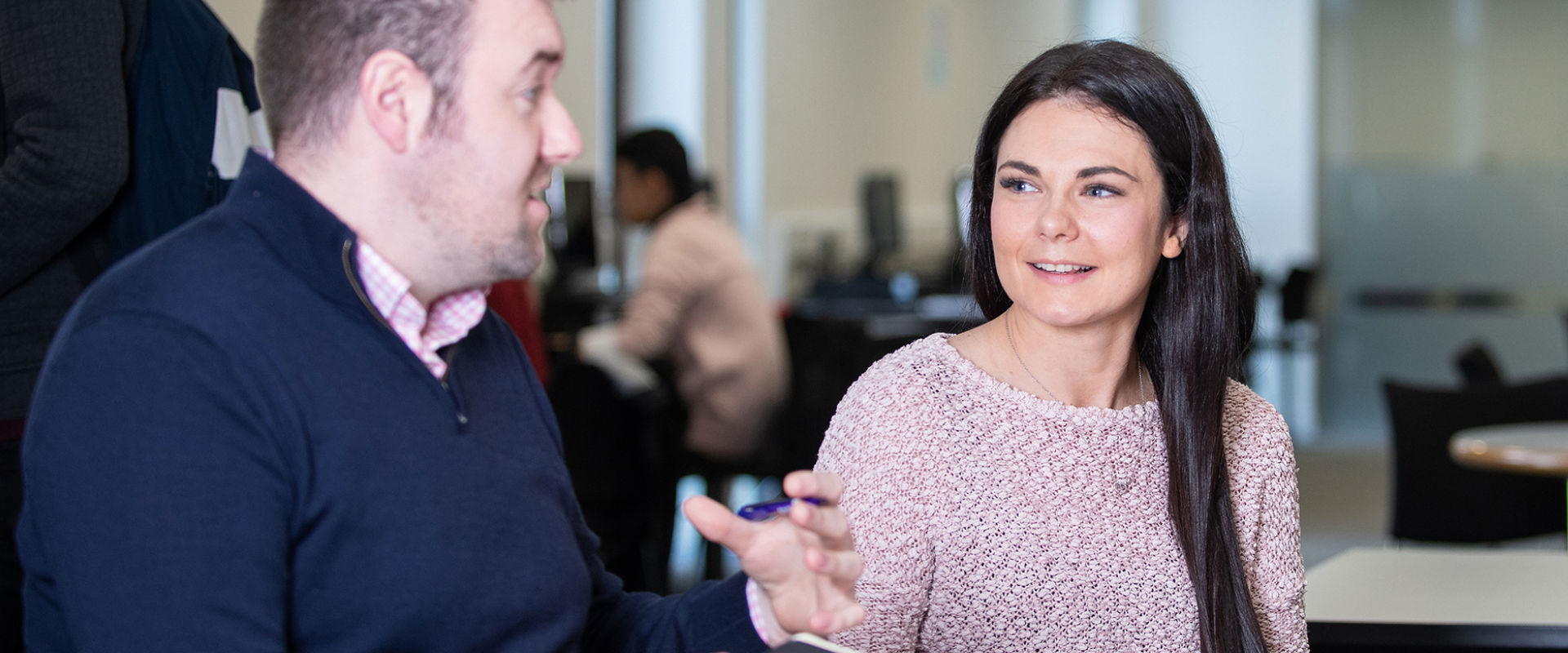 Two students looking at a notebook while talking to each other. 