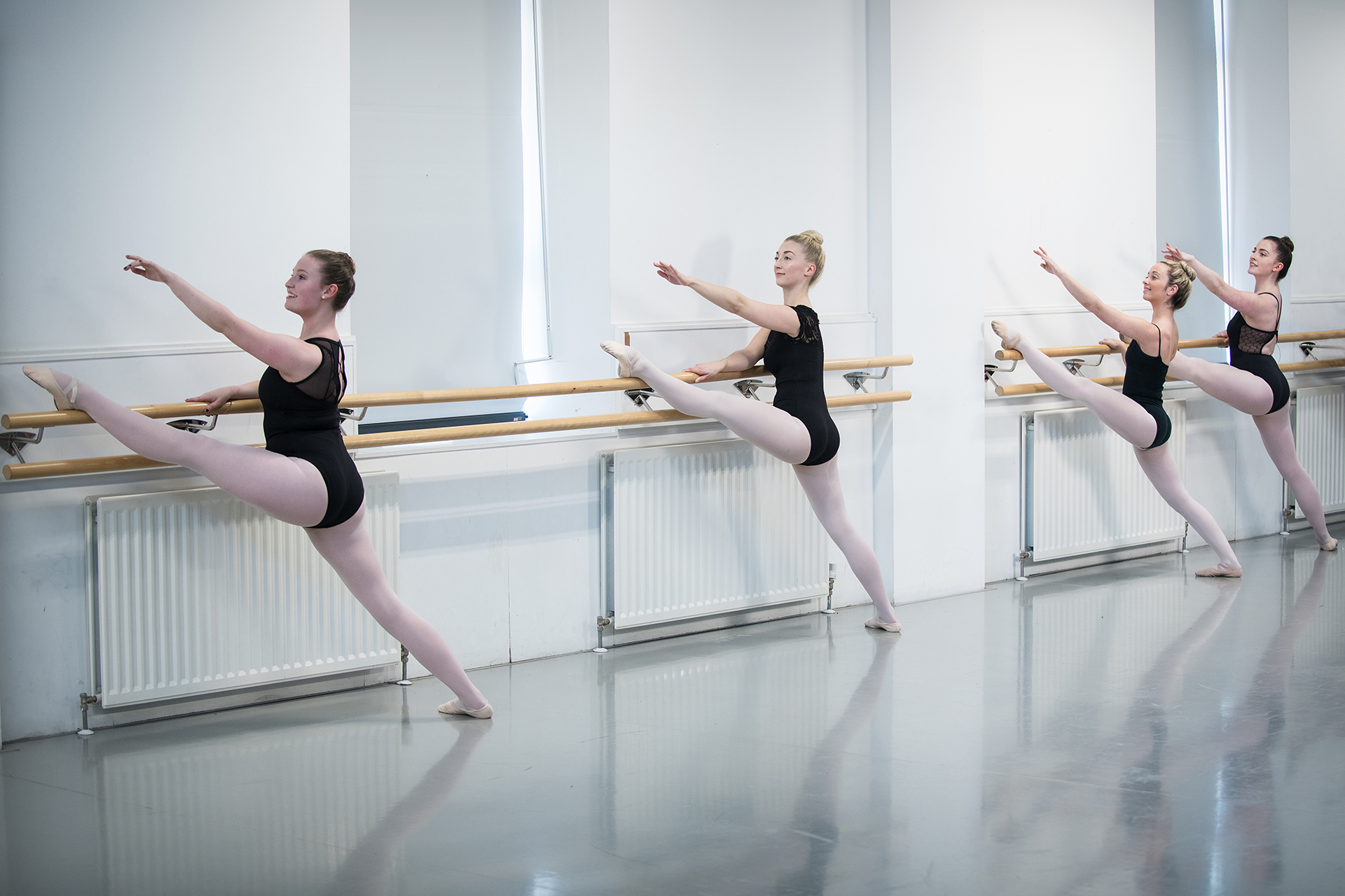 Dance students working on their ballet technique in a dance studio.